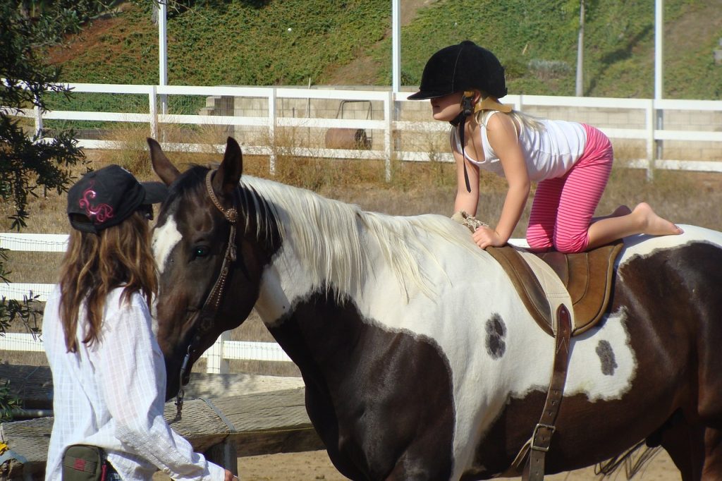 girl in classic jockey helmet getting onto a horse
